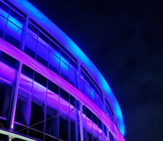 building at night illuminated in blue and purple by led neon strips