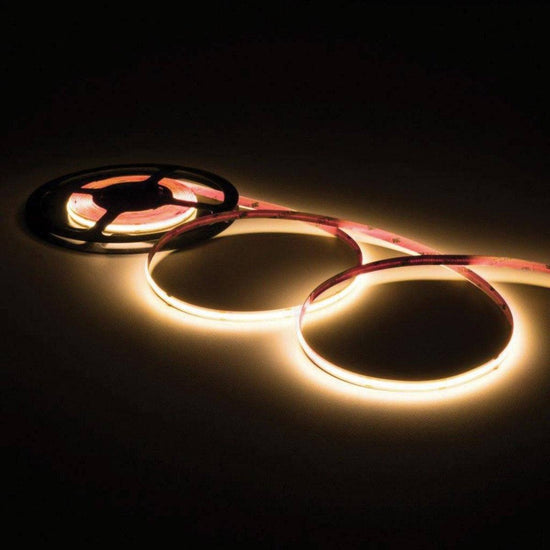 illuminated warm white led strip light loosely coiled three times off of a black reel