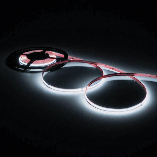 illuminated cool white colored led strip light loosely coiled three times off of a black reel