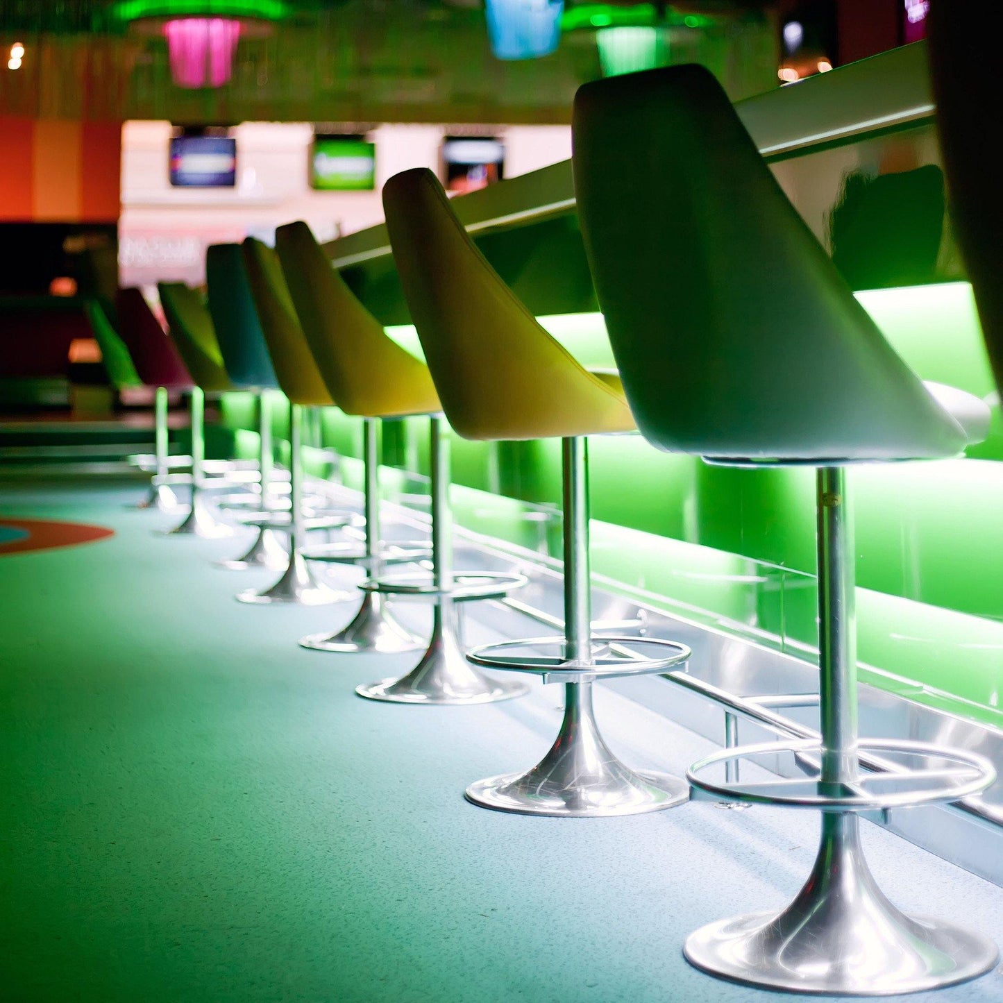 green hued bar with modern stool chairs illuminated by green strip light from under bar counter