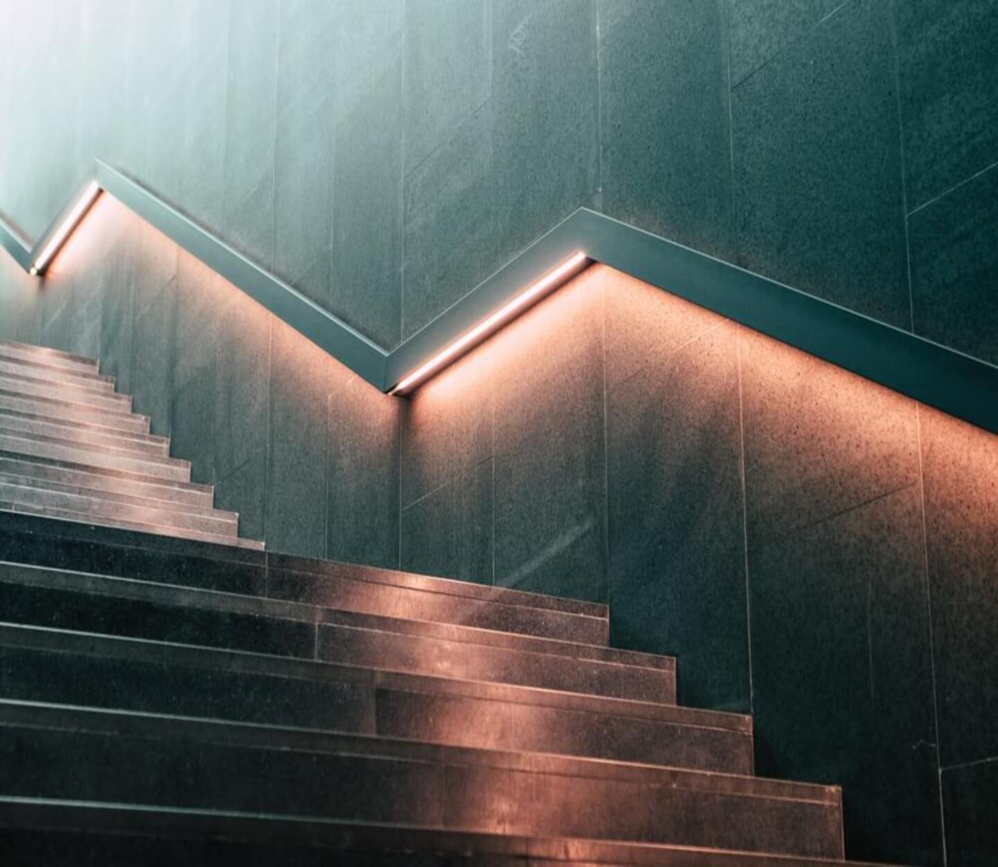 gray building staircase with rails illuminated by warm white strip lights