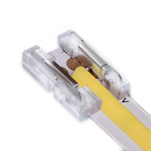 cob led strip light with visible yellow linear cover inserted into one side of a clear solderless connector with metal connection points