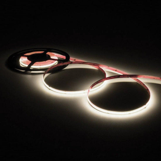 illuminated neutral white colored led strip light loosely coiled three times off of a black reel